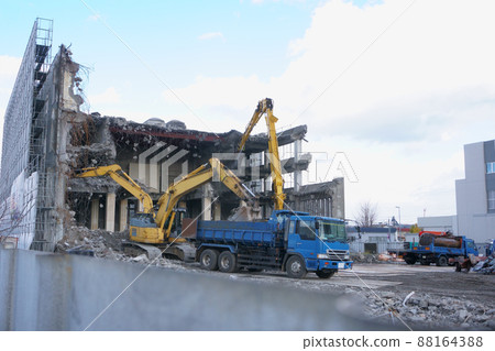 重型設備在自卸卡車上拆除破舊的公共建築時堆積瓦礫 重型設備在自卸卡車上拆除破舊的公共建築時堆積瓦礫 88164388