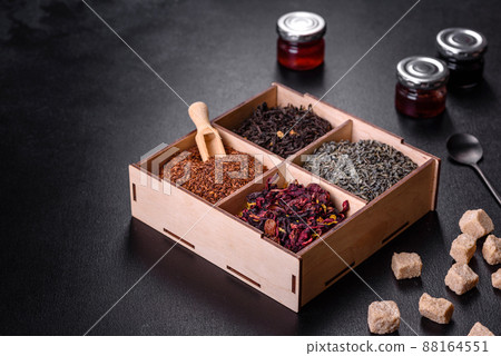 Several kinds of dry black tea with bergamot, rooibos, green and frame in a wooden box on a black concrete background Several kinds of dry black tea with bergamot, rooibos, green and frame in a wooden box on a black concrete background 88164551