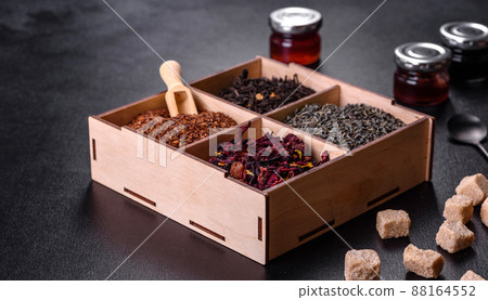 Several kinds of dry black tea with bergamot, rooibos, green and frame in a wooden box on a black concrete background Several kinds of dry black tea with bergamot, rooibos, green and frame in a wooden box on a black concrete background 88164552