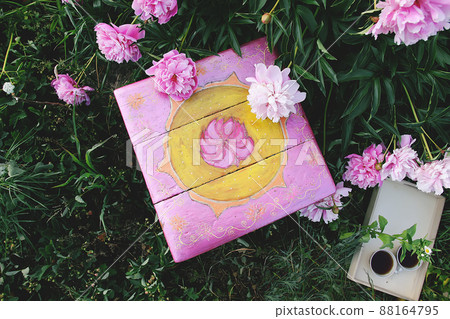 Old furniture restauration. Handmade old wooden stool painted with acrylic paints in summer garden in countryside with blooming beautiful peony flowers. 88164795