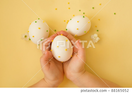 Easter eggs in the hands of a child. The religious holiday of Easter. The decor of Easter eggs. Eggs with polka dots on a yellow background. Easter eggs in the hands of a child. The religious holiday of Easter. The decor of Easter eggs. Eggs with polka dots on a yellow background. 88165052