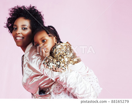 young pretty african-american mother with little cute daughter hugging, happy smiling on pink background, lifestyle modern people concept young pretty african-american mother with little cute daughter hugging, happy smiling on pink background, lifestyle modern people concept 88165279
