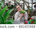 Young woman sells flowers and seedlings via video link on laptop via the Internet. Gardening, sales 88165988