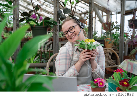 Young woman sells flowers and seedlings via video link on laptop via the Internet. Gardening, sales Young woman sells flowers and seedlings via video link on laptop via the Internet. Gardening, sales 88165988