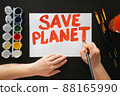 Human hands draw poster with paints and brush on blank sheet with call to save the planet. Rally, appeal, picket 88165990