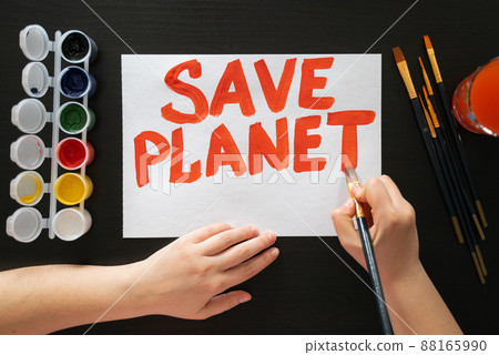 Human hands draw poster with paints and brush on blank sheet with call to save the planet. Rally, appeal, picket Human hands draw poster with paints and brush on blank sheet with call to save the planet. Rally, appeal, picket 88165990