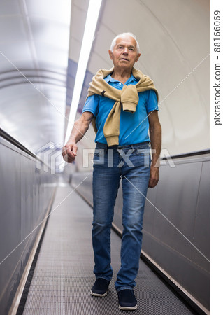 Positive mature man walking down escalator to subway station platform 88166069