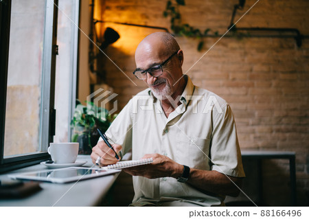 Successful male poet writing informative notes in paper textbook enjoying free time for creating, Successful male poet writing informative notes in paper textbook enjoying free time for creating, 88166496