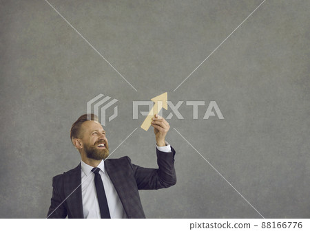 Happy businessman holding arrow going up as metaphor for business growth and success Happy businessman holding arrow going up as metaphor for business growth and success 88166776
