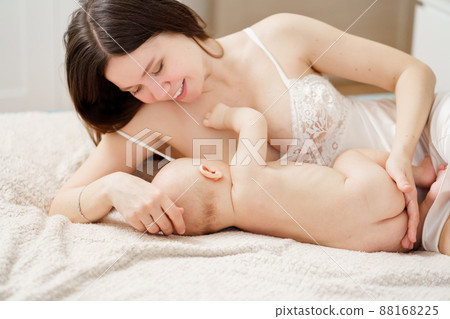 a mother feeds the baby with breast milk on the bed. the breastfeeding.  88168225