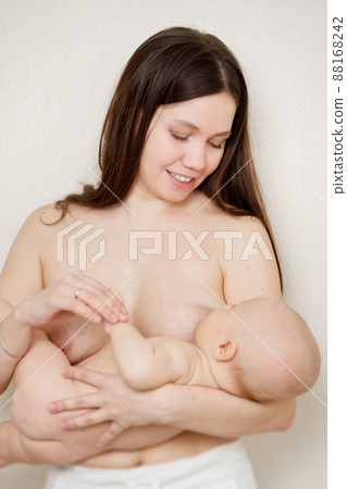 a naked mother feeds the baby with breast milk. the breastfeeding.  88168242