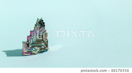 Synthetic bismuth Bismuthum crystal with iridescent oxide film on blue background close up isolated. Amazing colorful shiny rainbow Bismuth Gemstone mineral Synthetic bismuth Bismuthum crystal with iridescent oxide film on blue background close up isolated. Amazing colorful shiny rainbow Bismuth Gemstone mineral 88170358