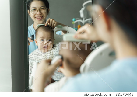 Smiling Asian Mother cutting and trimming her little baby boy hair 88170445