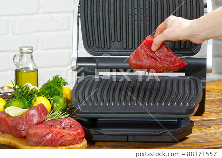 raw tuna steaks cooking on electric grill. 88171557