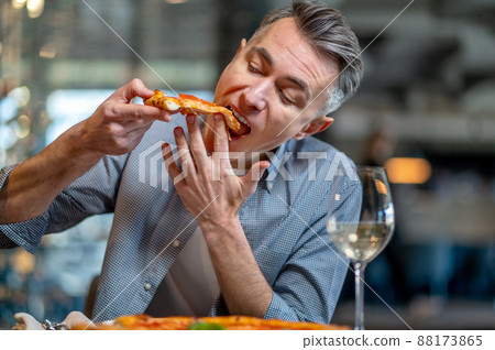 A man eating pizza and looking enjoyed A man eating pizza and looking enjoyed 88173865