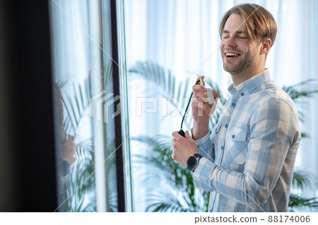 Happy and smiling man spraying perfume and looking contented Happy and smiling man spraying perfume and looking contented 88174006