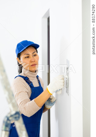 Woman builder using floated trowel to daub plaster to wall Woman builder using floated trowel to daub plaster to wall 88174290
