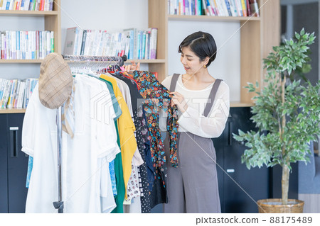 A young fashion editor choosing clothes from an office outfit rack A young fashion editor choosing clothes from an office outfit rack 88175489