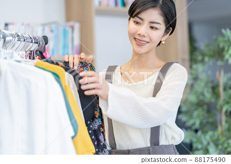 A young fashion editor choosing clothes from an office outfit rack A young fashion editor choosing clothes from an office outfit rack 88175490