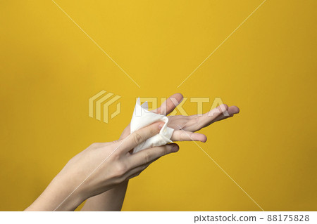 wet napkin in hands on yellow background 88175828