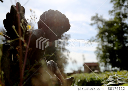 Beautiful Cupid angel statue with wings on back in vintage garden 88176112
