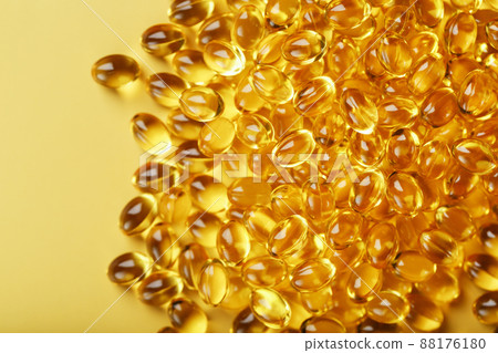 Heap of transparent fish oil capsules on yellow background with free space 88176180