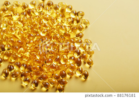 Pile of golden capsules of vitamin D3 on a yellow background with free space 88176181