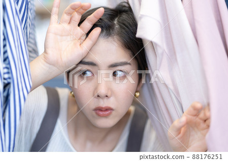 一位從辦公室衣架的服裝之間出現的年輕女性時尚編輯 一位從辦公室衣架的服裝之間出現的年輕女性時尚編輯 88176251