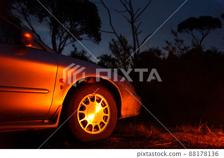 The color of the bonfire reflected on the car 88178136
