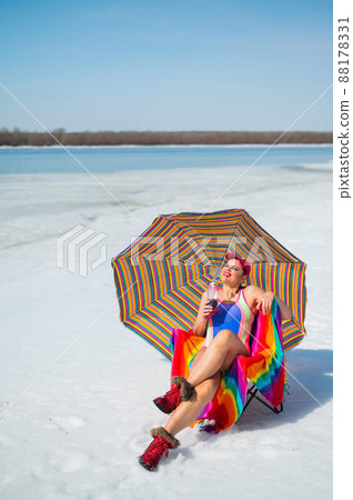 Caucasian woman in a swimsuit sunbathes on the snow in winter. Caucasian woman in a swimsuit sunbathes on the snow in winter. 88178331