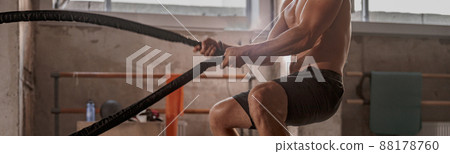 Young strong man battling with rope at gym 88178760