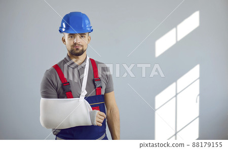Portrait of young builder who broke his arm in work accident at construction site Portrait of young builder who broke his arm in work accident at construction site 88179155