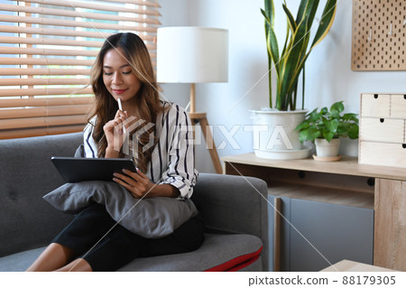 Cheerful young woman surfing internet, shopping online on digital tablet. 88179305