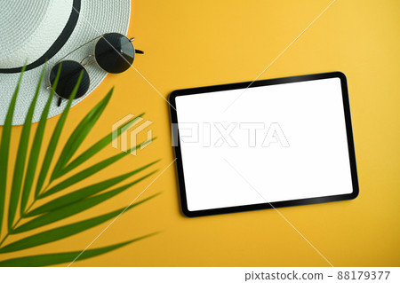 Flat lay digital tablet, sunglasses ,hat and tropical palm leaves on yellow background. Summer vacation concept. Flat lay digital tablet, sunglasses ,hat and tropical palm leaves on yellow background. Summer vacation concept. 88179377
