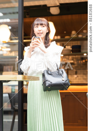 一個從咖啡館出來的年輕女子，她喝了一杯 88181688