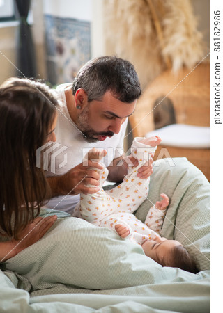 Happy couple playing with baby son in bed Happy couple playing with baby son in bed 88182986