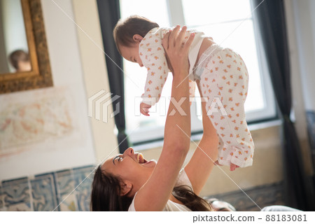 Excited mother tossing her baby son in bedroom Excited mother tossing her baby son in bedroom 88183081