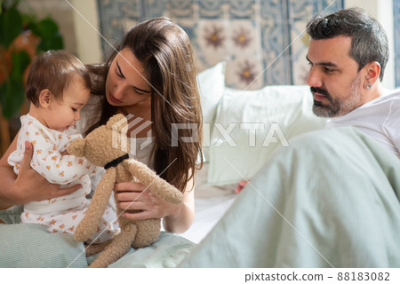 Happy family sitting together in bed with baby son Happy family sitting together in bed with baby son 88183082