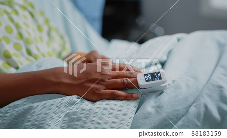 Close up of oximeter on finger of patient with illness in hospital ward bed. Sick woman having tool to measure oxygen saturation and pulse pressure to cure disease. Medical care 88183159