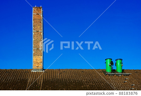 Minimalist abstract image of chimneys on a roof in front of bright blue sky 88183876