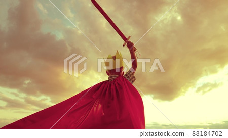 boy plays superhero against backdrop sunset sky. small child kid red cape with sword his hand. child dream kid. boy golden crown plays game. costume children's fantasy happy baby vacation holiday. boy plays superhero against backdrop sunset sky. small child kid red cape with sword his hand. child dream kid. boy golden crown plays game. costume children's fantasy happy baby vacation holiday. 88184702