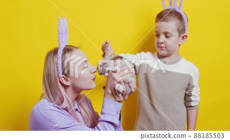 A girl and a boy with bunny ears on a yellow background. A girl is holding a rabbit. Easter A girl and a boy with bunny ears on a yellow background. A girl is holding a rabbit. Easter 88185503