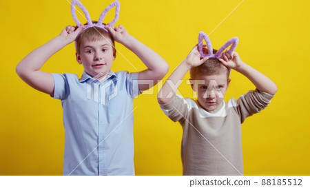 Two boys with rabbit ears on a yellow background. Easter Two boys with rabbit ears on a yellow background. Easter 88185512