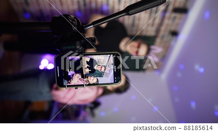 Vertical photo. A guy and a girl shoot a blog on their phone. A view of the phone screen standing on a tripod. Social network. Blogger 88185614