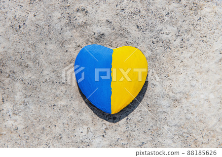 Stone in shape of a heart painted with the Ukrainian flag lies on the ground or concrete. No war. Stop the war, the genocide of Ukrainians. Flat lay with copy space. Save Ukraine people from invasion. Stone in shape of a heart painted with the Ukrainian flag lies on the ground or concrete. No war. Stop the war, the genocide of Ukrainians. Flat lay with copy space. Save Ukraine people from invasion. 88185626