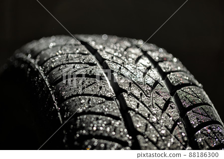 Water splashing on new car tyre closeup 88186300