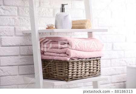 Basket with clean towels on shelving unit in bathroom Basket with clean towels on shelving unit in bathroom 88186313