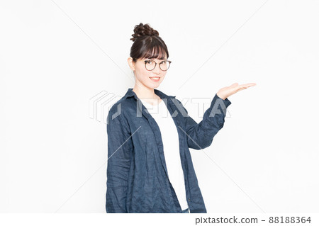一個戴眼鏡的女人站在白色背景前做引導手勢 88188364