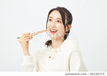 A woman eating with a chopstick 88190379