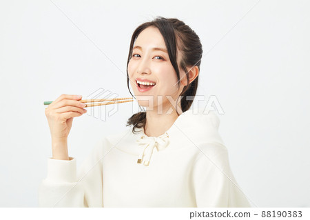 A woman eating with a chopstick A woman eating with a chopstick 88190383